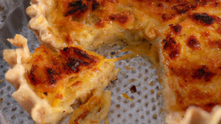 Imagem de uma quiche recém-assada em uma assadeira de ar. A quiche tem uma crosta dourada e um recheio cremoso com vegetais coloridos.