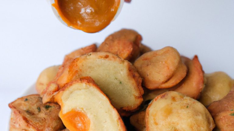 Imagem de uma Airfryer com frango empanado dourado e crocante dentro, acompanhado de uma tigela de molho.