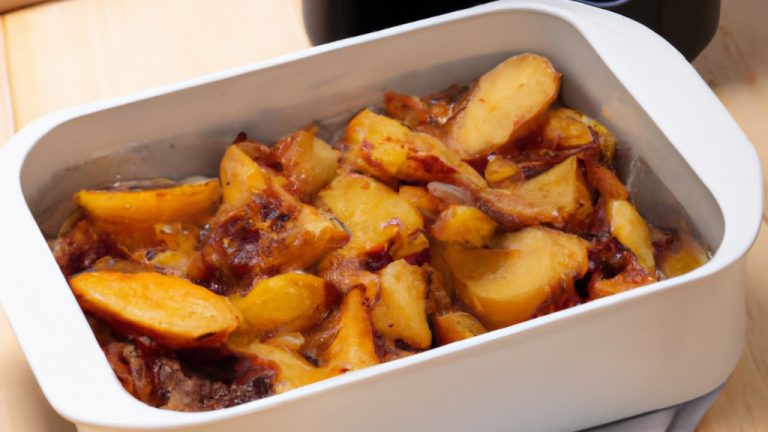 Uma foto do prato Ratatouille feito em uma airfryer. O prato é composto por vegetais coloridos, como berinjela, abobrinha, pimentão e tomate, cortados em cubos e dispostos em um padrão intrincado. O prato está dourado e borbulhante, com gotas de azeite de oliva por cima.