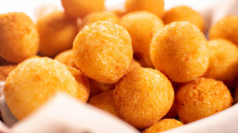 Imagem de bolinhas de queijo douradas e crocantes feitas na airfryer, usando apenas três ingredientes: queijo mussarela, ovo e farinha de rosca. As bolinhas são apresentadas em um prato forrado com papel toalha, prontas para serem saboreadas.