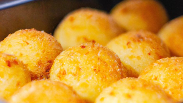 Imagem de bolinhos de arroz quentes e dourados cozidos em uma Airfryer, recheados com queijo derretido e polvilhados com cebolinha. Esses bolinhos crocantes e cremosos são um lanche ou aperitivo perfeito.