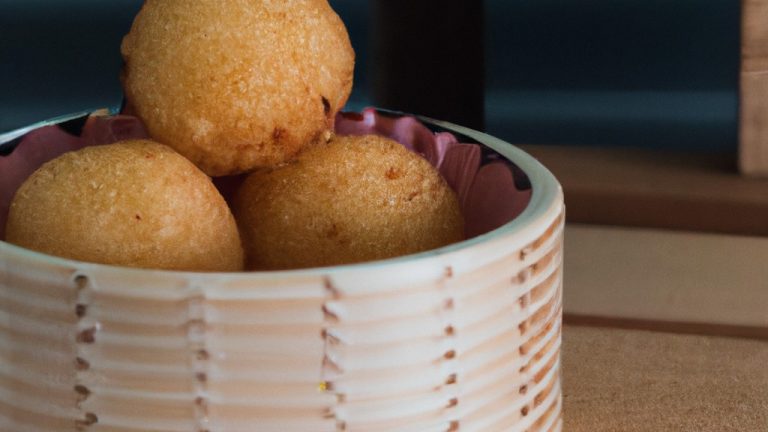 Uma imagem de bolinhos de arroz crocantes e dourados feitos na Airfryer. Eles são feitos com apenas 2 ingredientes: arroz cozido e óleo. Os bolinhos são servidos em um prato com um molho de soja opcional.