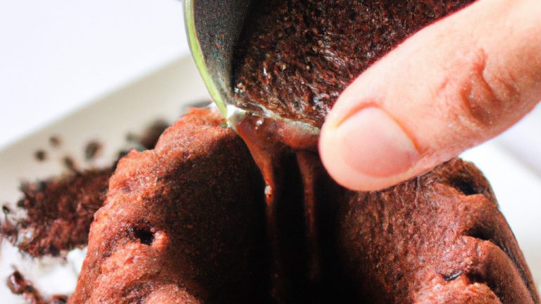 Imagem de um bolo de chocolate assado em uma Airfryer, coberto com uma cobertura de ganache. O bolo é feito com farinha, açúcar, cacau em pó, fermento em pó, bicarbonato de sódio, sal, leite, óleo vegetal e extrato de baunilha. A cobertura é feita com chocolate meio amargo e creme de leite.