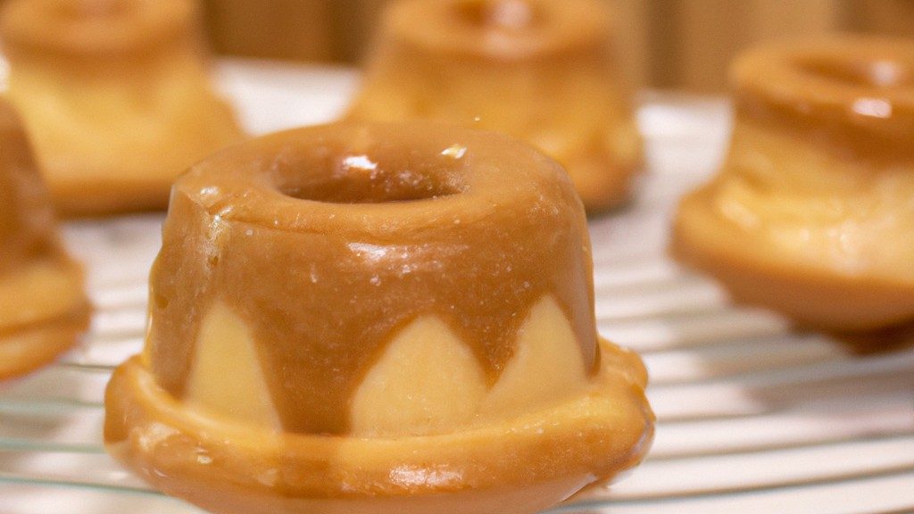 Imagem de um petit gateau com recheio de doce de leite, cozido em uma airfryer. O petit gateau está em um prato branco, com uma colher ao lado. O recheio de doce de leite é visível no centro do petit gateau.
