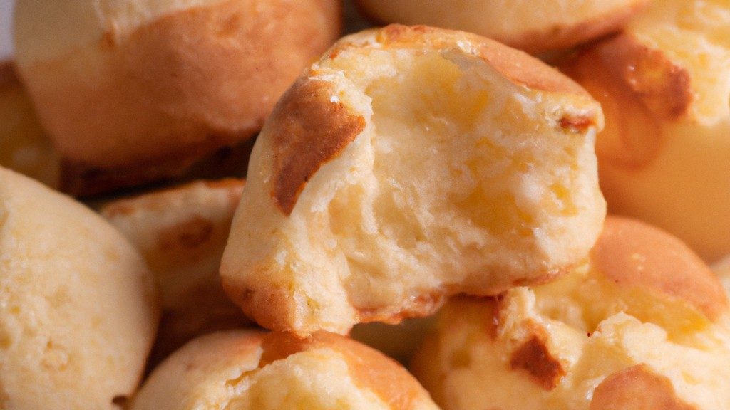Imagem mostrando um bolo de pão de queijo dourado e recém-assado em uma Airfryer, cercado por ingredientes como polvilho azedo, queijo parmesão e ovos.