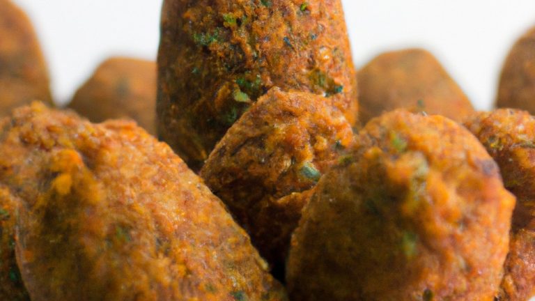 Imagem de um prato de kibe de macaxeira dourado e crocante feito na Airfryer. A macaxeira ralada e temperada é moldada em formato de croquetes e cozida até ficar dourada e crocante. O kibe é servido com uma porção de coalhada seca para acompanhar.