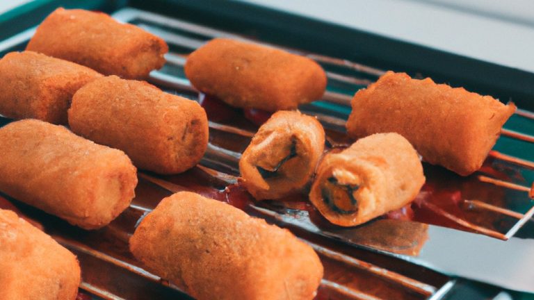 Imagem de risoles fritos na airfryer, com recheio de carne moída e queijo. Os risoles estão dispostos em um prato, com um fundo de papel toalha absorvente.