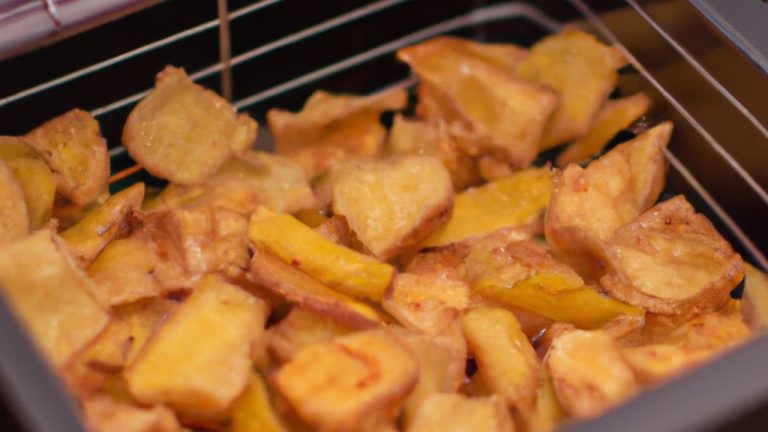 Imagem de salgadinhos de batata-doce crocantes e dourados preparados na Airfryer, servidos em uma tigela com um molho ao lado.