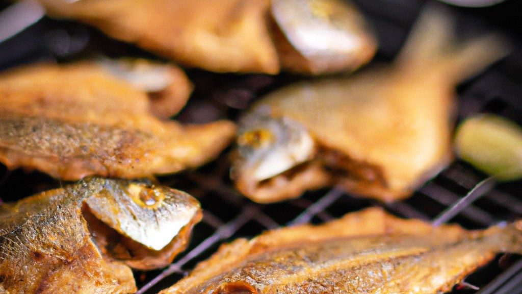 Imagem de sardinhas assadas na Airfryer, dispostas em uma cesta de metal. As sardinhas têm pele crocante, dourada e escamas visíveis. Elas estão temperadas com ervas e especiarias e exalam um aroma delicioso.