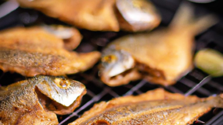 Imagem de sardinhas assadas na Airfryer, dispostas em uma cesta de metal. As sardinhas têm pele crocante, dourada e escamas visíveis. Elas estão temperadas com ervas e especiarias e exalam um aroma delicioso.