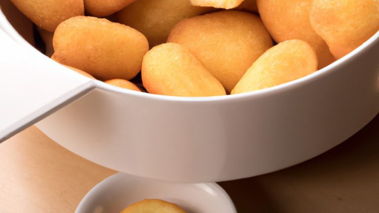 Imagem de um suflê de queijo dourado e fofo em uma tigela branca. O suflê é coberto com ervas frescas e está em uma superfície de madeira.