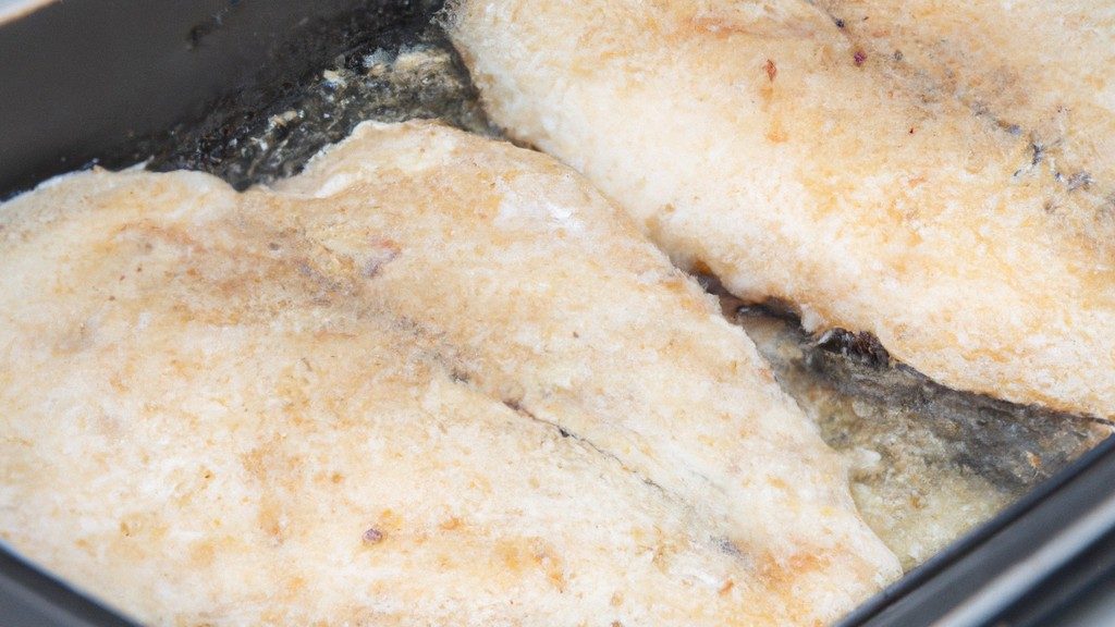 Uma tilápia inteira congelada em uma airfryer, mostrando sua pele dourada e crocante. A tilápia é colocada sobre uma cama de limão e ervas, e está pronta para ser servida.