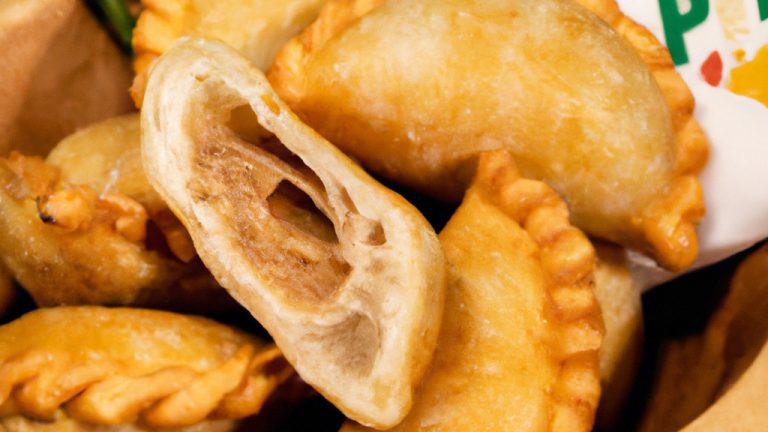 Foto de tilápias empanadas crocantes e douradas cozinhando em uma airfryer. A imagem mostra os filés de peixe empanados em uma cesta de airfryer, com um fundo de limão, salsa e coentro.