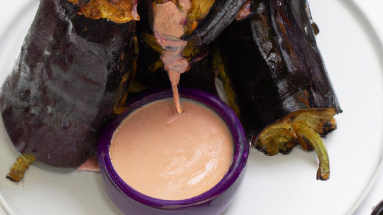 Foto de uma torre de berinjela assada em uma Airfryer. As fatias de berinjela são empilhadas verticalmente com uma crosta dourada e crocante, mostrando o interior macio e cozido. A imagem é acompanhada do texto "Torre De Berinjela Na Airfryer: Receita Diferente E Deliciosa".