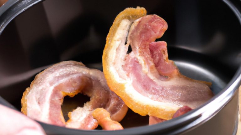 Imagem de uma porção de torresmo de bacon crocante e dourado cozido na airfryer, com gotas de gordura ao redor. O bacon é fatiado e disposto em uma única camada na cesta da airfryer.