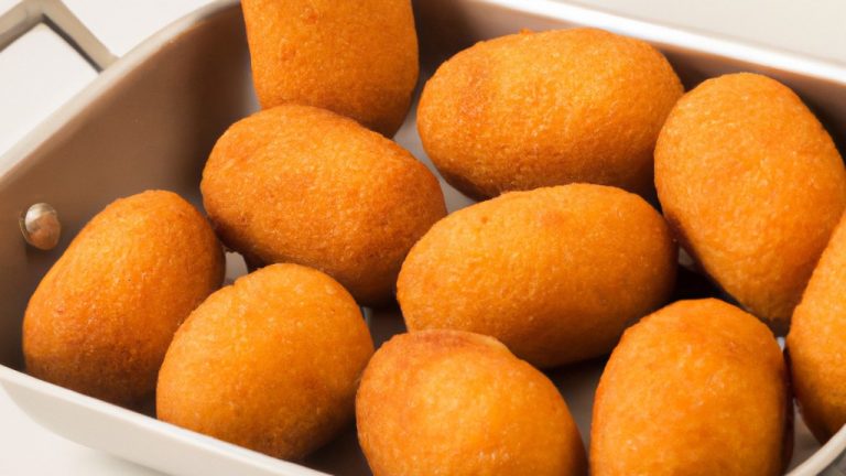 Uma fotografia aérea de uma Air Fryer Britânia Bella Cuccina em uma bancada de cozinha branca. A fritadeira de ar é preta e tem um cesto antiaderente. Há um livro de receitas ao lado da fritadeira de ar.