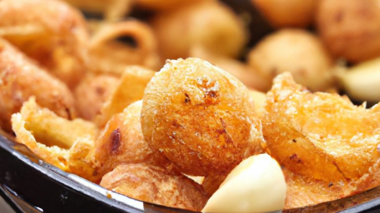 Imagem de alho assado na Airfryer. Os dentes de alho estão dourados e caramelizados, com uma textura macia e cremosa. O alho é apresentado em uma tigela branca contra um fundo de madeira.