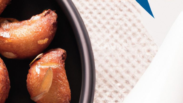 Imagem de almôndegas douradas e crocantes cozidas em uma airfryer, servidas em um prato com um molho de tomate vermelho ao lado.