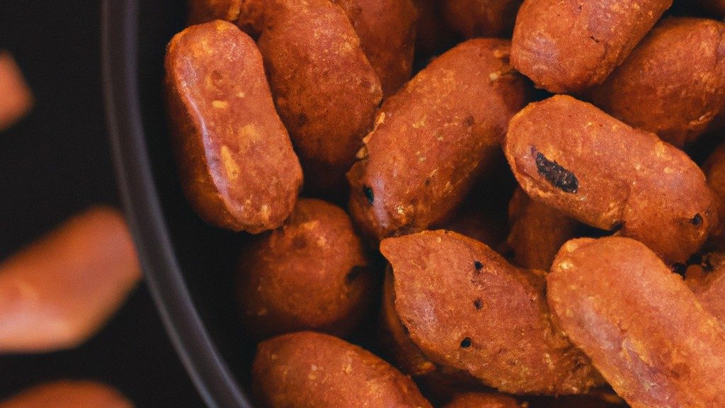 Imagem de amendoins torrados em uma airfryer. Os amendoins são de cor marrom-dourada e estão em uma cesta de metal.