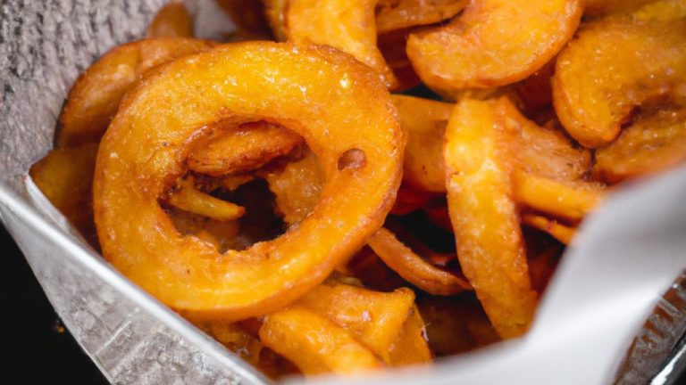 Foto de batatas doces cortadas em fatias grossas e fritas em uma Airfryer. As batatas são douradas e crocantes, com uma polpa macia e amanteigada no interior. Elas são temperadas com sal, pimenta e páprica, e servidas com um molho de iogurte grego.