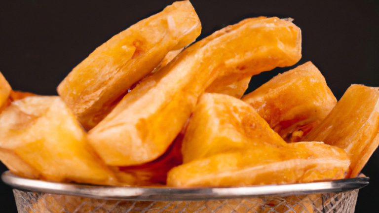 Batata-doce rústica crocante e dourada, assada na Airfryer. A casca enrugada exibe um tom marrom-avermelhado, contrastando com a polpa laranja vibrante no interior. As bordas das fatias são ligeiramente enroladas, criando uma textura crocante e convidativa.