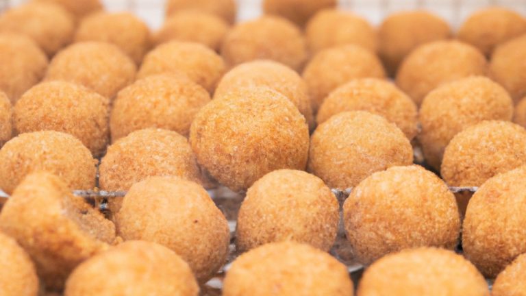 Imagem de bolinhos crocantes e dourados de feijoada, feitos na Airfryer. Os bolinhos são recheados com uma mistura saborosa de feijão preto, carne de porco e temperos, e são servidos com um molho de pimenta saboroso.