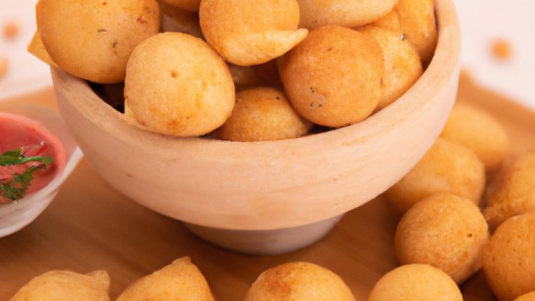 Imagem de bolinhos de bacalhau dourados e crocantes empilhados em um prato. Eles são feitos com bacalhau desfiado, batatas, cebola, alho e temperos, e são cozidos em uma airfryer até ficarem perfeitamente cozidos e crocantes.