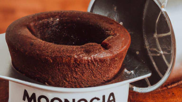 Imagem de um bolo de chocolate assado na Airfryer. O bolo é úmido e fofo, com uma crosta crocante. É decorado com uma cobertura de chocolate e granulado colorido.