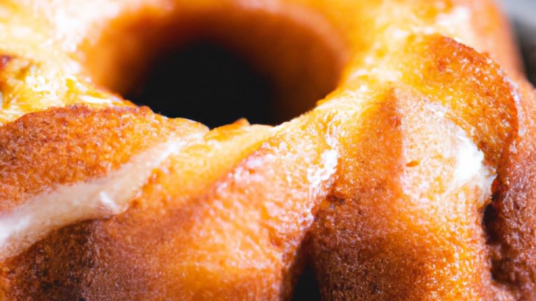 Imagem de um bolo de fubá cremoso dourado cozido em uma airfryer. O bolo tem uma crosta crocante e um miolo úmido e denso. É coberto com uma camada de glacê de cream cheese e decorado com nozes picadas.