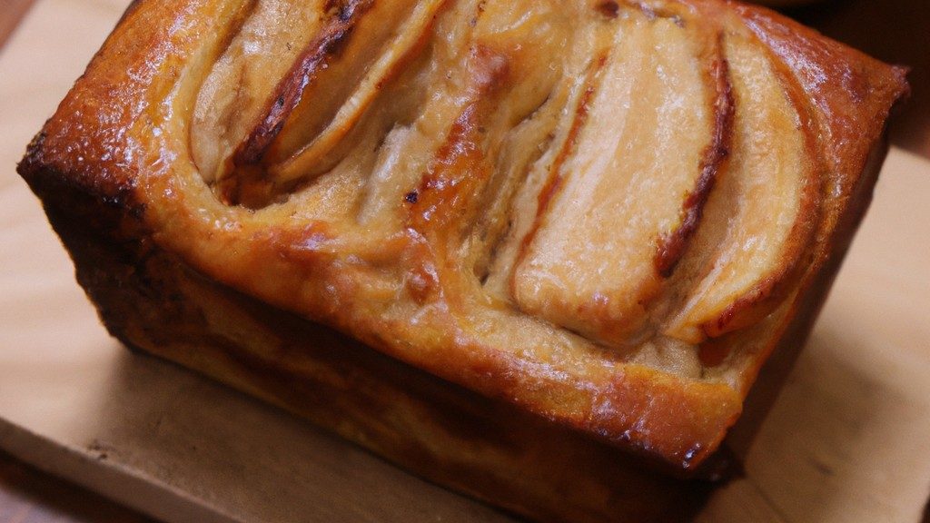 Imagem de uma airfryer com um bolo de maçã e passas assado dentro. O bolo é dourado e tem uma crosta crocante, com maçãs e passas visíveis na superfície.