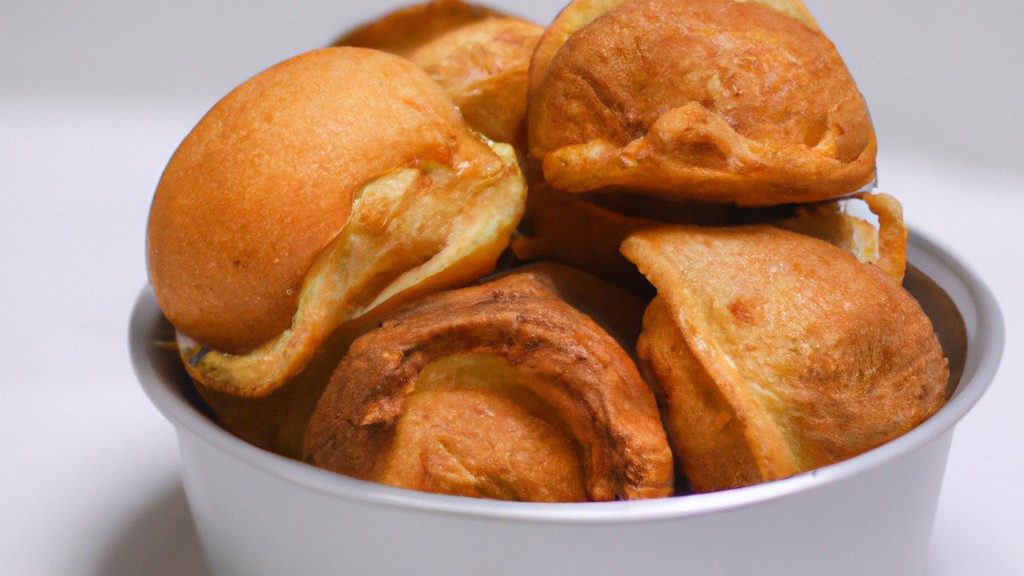 Imagem de uma broa de fubá crocante e dourada feita na airfryer. A broa tem uma crosta crocante e um interior macio e úmido. Ela é servida em um prato com uma porção de manteiga derretida ao lado.