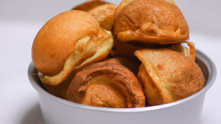 Imagem de uma broa de fubá crocante e dourada feita na airfryer. A broa tem uma crosta crocante e um interior macio e úmido. Ela é servida em um prato com uma porção de manteiga derretida ao lado.