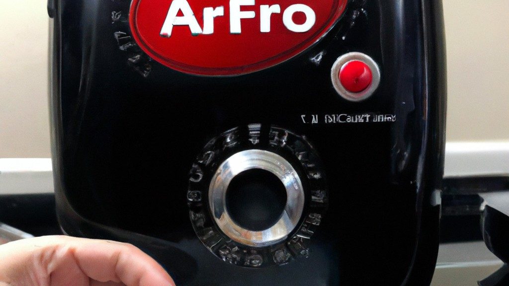 Imagem mostrando uma airfryer branca e cinza com uma cesta removível. A airfryer está sobre uma superfície de cozinha branca com utensílios de cozinha e ingredientes ao redor. O texto "Chegou Minha Airfryer, E Agora? / Primeiros Passos!" está escrito na parte superior da imagem.