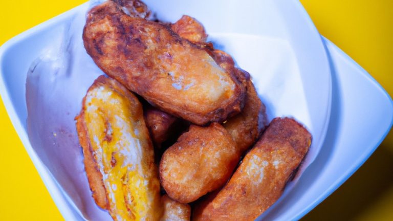 Uma imagem de bananas fatiadas cobertas com uma mistura de canela e açúcar dentro de uma fritadeira airfryer. As bananas estão douradas e crocantes.