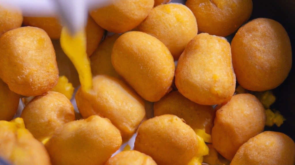 Imagem de uma polenta frita dourada em formato de palitos, servida em um prato com um molho de tomate ao lado.