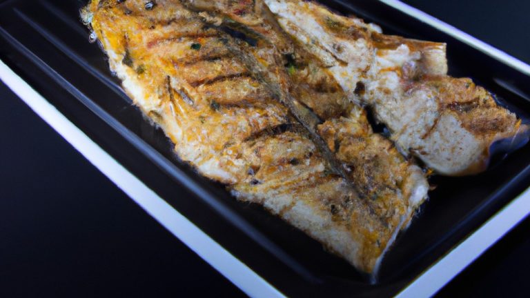 Imagem de um filé de tilápia assado na airfryer. O filé é dourado e crocante, com as bordas ligeiramente enroladas. É apresentado em um prato com uma fatia de limão e um raminho de ervas frescas.