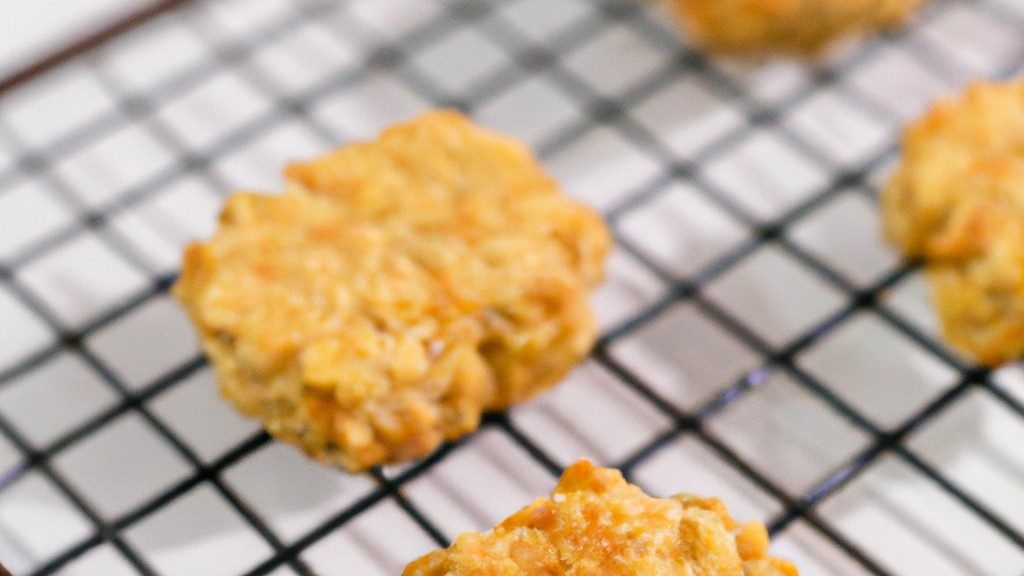 Imagem de cookies de banana e aveia dourados e crocantes dispostos em uma cesta de arame. Os cookies são feitos com uma mistura de aveia, purê de banana, farinha de trigo integral e especiarias, resultando em uma textura macia e mastigável com um sabor doce e frutado.
