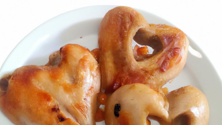 Imagem de uma porção de corações de galinha cozidos em uma airfryer. Os corações estão dourados e crocantes, com um leve tom vermelho no centro. Eles são servidos em um prato branco, com uma tigela de molho ao lado.