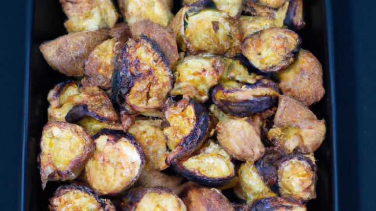 Foto de dadinhos de berinjela fritos em uma airfryer. Os dadinhos são dourados e crocantes, parecidos com pipoca.