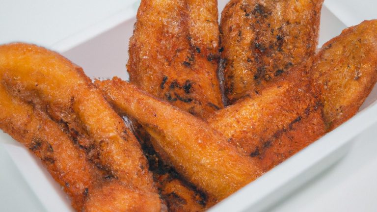 Imagem de bananas fatiadas em rodelas em uma Airfryer. As bananas estão cobertas com uma camada crocante e dourada. A Airfryer é um eletrodoméstico de cozinha que circula ar quente para cozinhar alimentos de forma rápida e uniforme.