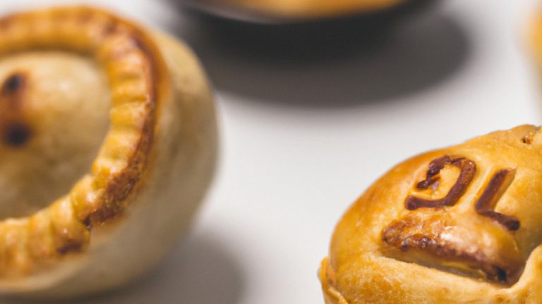 Imagem de uma empadinha assada em uma Airfryer. A empadinha tem uma crosta dourada e crocante, e o recheio é visível através de um pequeno orifício no topo. A empadinha é colocada em um prato branco com uma espátula ao lado. O fundo é branco.