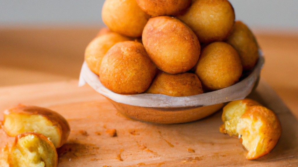 Imagem de uma airfryer com frango empanado cozinhando dentro dela. O fundo é uma superfície de madeira escura e há um recipiente com óleo de cozinha ao lado da airfryer.