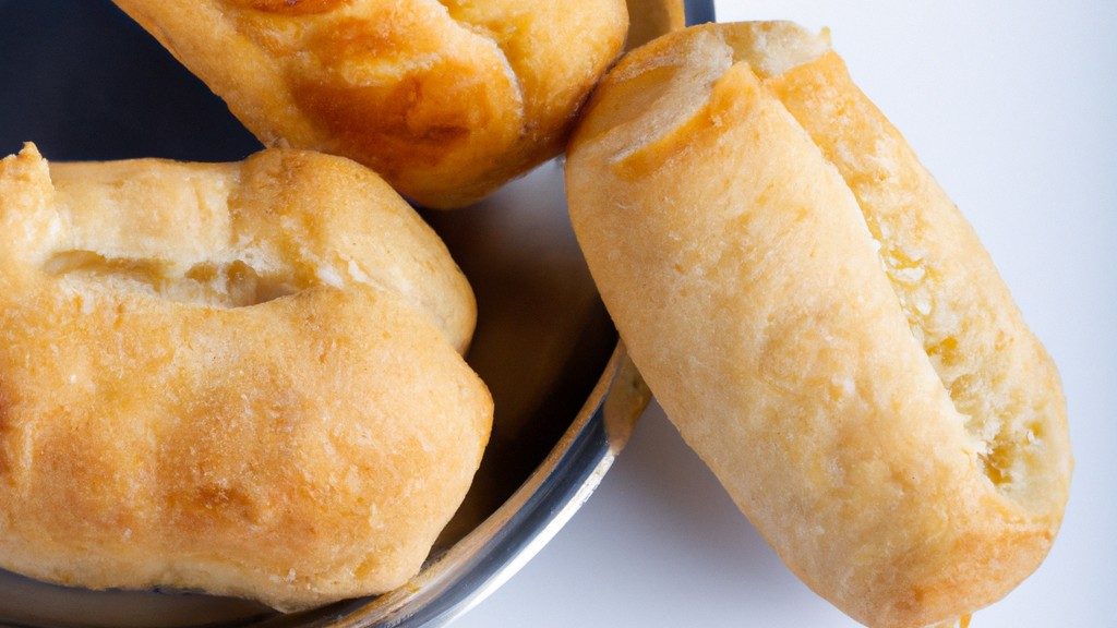 Imagem de uma esfiha aberta e dourada, feita na airfryer, com recheio à mostra, como carne moída, cebola e pimentão.