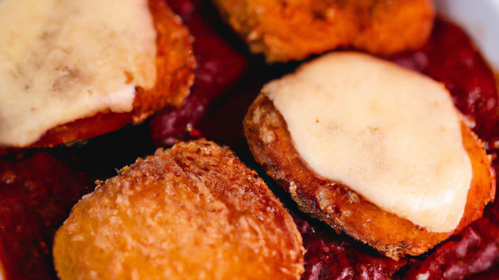 Filé de frango empanado e frito à milanesa, coberto com molho de tomate e queijo, gratinado na Airfryer. A imagem mostra o filé em um prato, com uma fatia de limão ao lado.