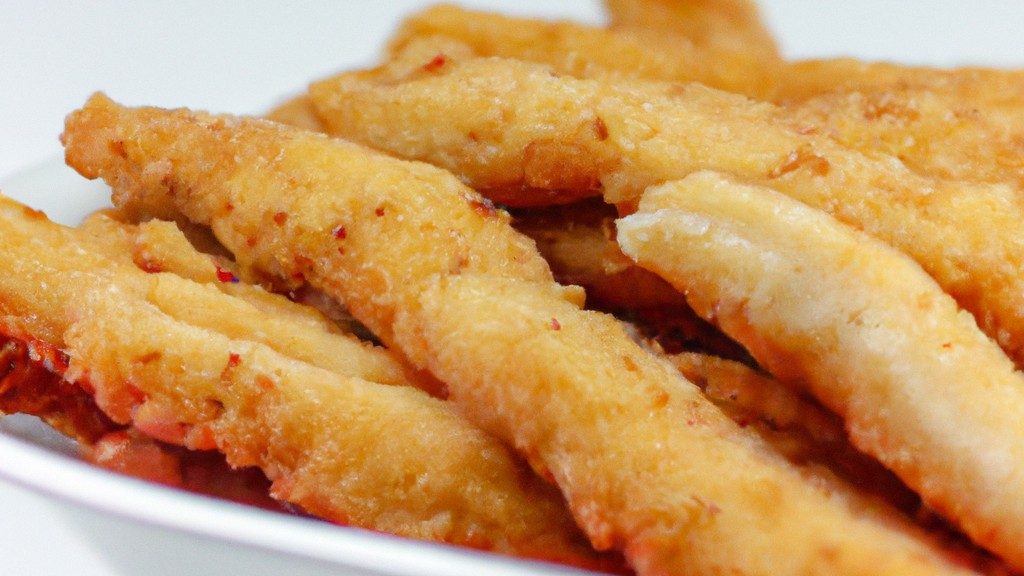 Imagem de filés de peixe empanados fritos na airfryer, crocantes e dourados, acompanhados de molho tártaro e limão.