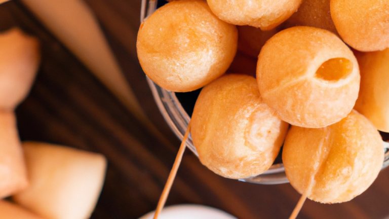 Imagem de uma Airfryer com uma cesta contendo uma panela de fondue de queijo quente e borbulhante. Ao lado da panela, há uma variedade de itens para mergulhar, como pedaços de pão, vegetais crus, frutas e chocolates. O fundo da imagem é uma mesa de madeira com uma toalha de mesa xadrez vermelha e branca. O texto na imagem diz "Fondue Completo Na Airfryer - Salgado E Doce".
