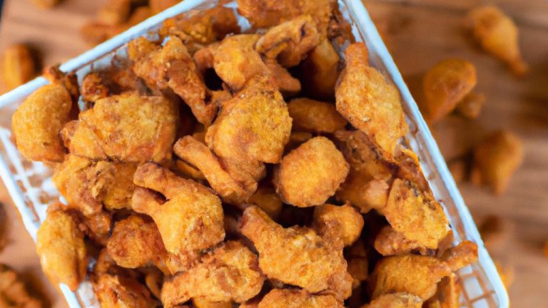 Imagem de frango frito crocante preparado na Airfryer. Os pedaços de frango têm uma crosta dourada e crocante, com carne suculenta e macia por dentro. O frango é servido em um prato forrado com papel toalha para absorver o excesso de óleo.