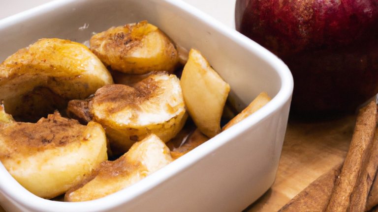Imagem de maçãs cortadas em fatias finas, polvilhadas com canela, colocadas na cesta de uma Airfryer. As maçãs estão douradas e caramelizadas, com uma crosta crocante.