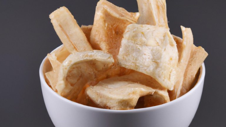 Imagem de mandioca frita na airfryer, com exterior crocante e dourado e interior macio e branco. Os palitos de mandioca são dispostos em uma cesta de airfryer, com um pouco de sal e pimenta polvilhados por cima.