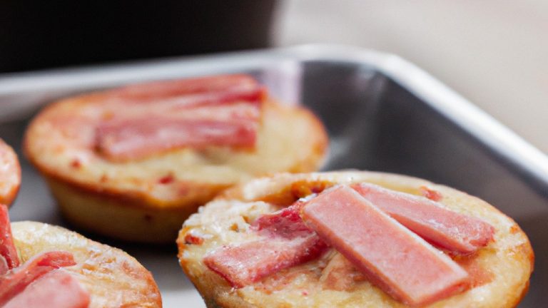 Imagem mostra mini pizzas caseiras preparadas na Airfryer. As pizzas têm uma crosta dourada e crocante, cobertas com uma camada fina de molho de tomate, queijo derretido e vários ingredientes como pepperoni, cogumelos, pimentões e cebolas. As pizzas são apresentadas em uma cesta forrada com papel manteiga, prontas para serem saboreadas.